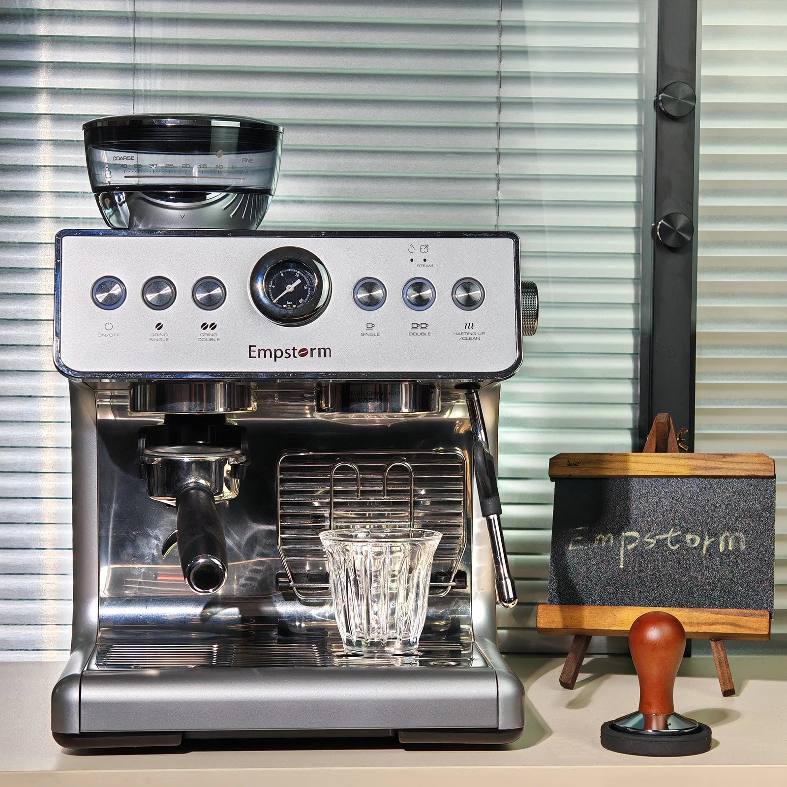 Empstorm espresso machine on a counter with a small stand and tamper in the background.
