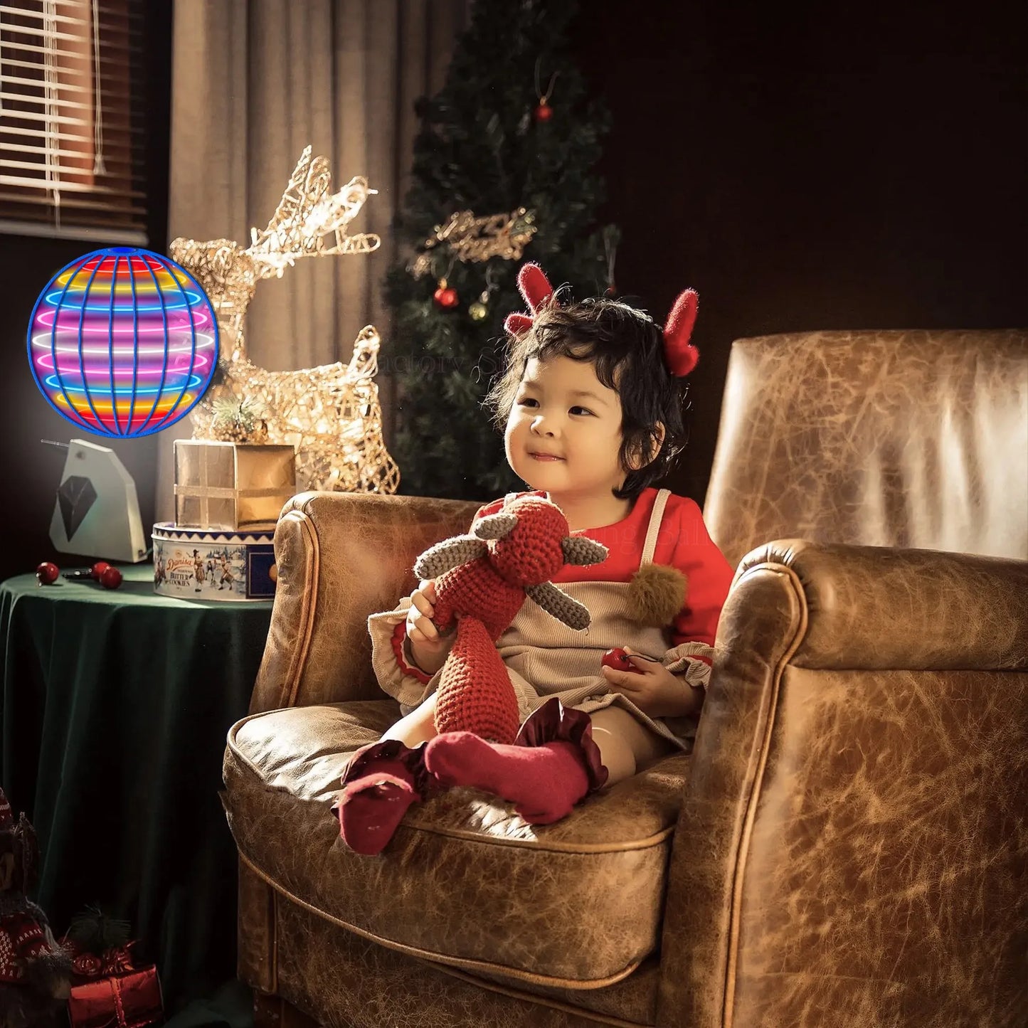 Child sitting on a brown armchair holding a plush toy, with a Christmas tree and decorations in the background.